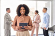 © insta_photos - Happy young African American business woman standing in office lobby. Smiling confident professional female company employee leader manager holding tablet looking at camera. Portrait.