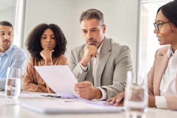 Aufkleber - Serious senior Latin business man investor checking bank document at office team meeting with financial law experts lawyers attorneys team thinking of risks. Consultancy advisory services concept.
