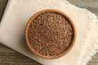 Bowl of caraway seeds and napkin on wooden table, top view