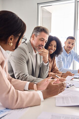 Busy diverse professional business team having discussion at office meeting. Financial advisors or managers consulting senior business man investor talking sitting at conference table. Vertical shot.