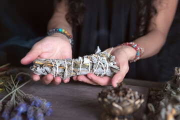 woman doing traditional ritual with herbs tying them with cotton thread accompanied by incense