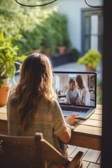 Rear view of young woman using laptop on terrace during video call