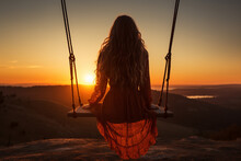 Young Woman Sitting On A Swing At Sunset In The Mountains. Rear View.