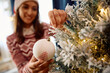 Close up of woman decorating Christmas tree at home.