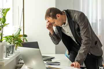 Frustrated dazed caucasian man, company employee, product manager, ceo, sitting at workplace in the office, looking at financial documents in surprise, dissatisfied with the result of work