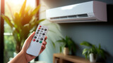 Fototapeta  - Hand holding an air conditioner remote, Air conditioner inside the room with woman operating remote controller.