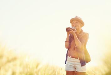 Wall Mural - Outdoor, sunshine and woman with a camera, photographer and travelling with happiness, lens flare and adventure. Trip, photography or girl with nature, field or summer with vacation, picture or smile