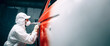 © Рика Тс - A car painter in a white protective suit paints a car with red spray paint. Copy space. Banner.