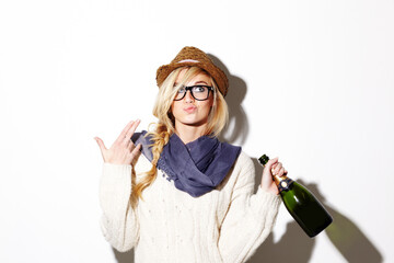 Woman, blonde and hat with champagne of nerd, geek or hipster thinking against a studio background. Attractive female person with glasses, nerdy or fashion style gesture and holding bottle of alcohol