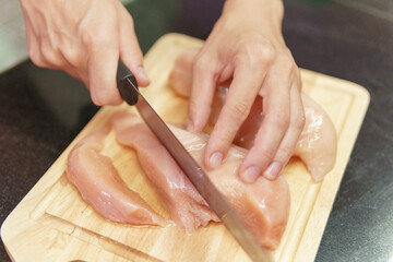 Canvas Print - Woman hands slicing fresh chicken breasts on a cutting board