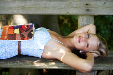 Canvas Print - Portrait, relax and book with woman on park bench for literature, summer and happiness. Calm, nature and peace with young female person reading in countryside for knowledge, learning and studying