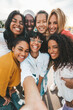 © Davide Angelini - Multicultural young women taking selfie with smart mobile phone device outside - Happy group of girls simling together at camera - Youth community with female friends having fun outside - Vertical pic