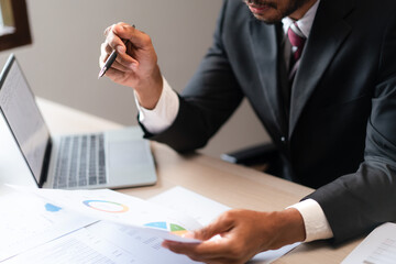 Wall Mural - Businessman read marketing graph paper and checking data on laptop to analyzing strategy of startup