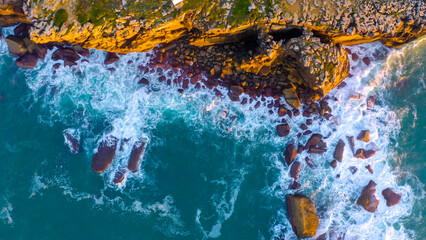 Aerial view of the ocean rocky shore. aerial view of green ocean waves splash on cliff. 