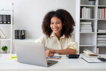 Wall Mural - African American businesswoman sitting at the desk in front of the laptop and thinking.