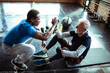 © Davor - Elderly man getting support from a personal trainer in the gym
