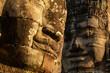 Two stone faces, sculpted at Bayon temple, illuminated by the last rays of evening sunlight, Angkor, Cambodia.