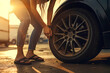 partial view of woman wearing jeans and sandals checking or changing a tire