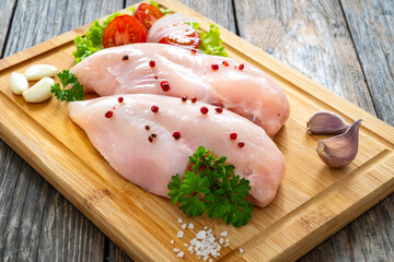 Wall Mural - Fresh raw chicken breasts on cutting board with spices on wooden background
