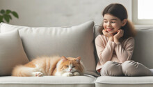 A Young Smiling Girl Sits On The Sofa Next To Her Fluffy Kitten