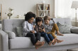 © fizkes - Three multiethnic little boys spend time on internet sit together on sofa look at phone screen, laugh, watching funny video, use new application. Modern tech and younger generation, bad habit, overuse
