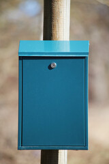 A blue iron mailbox hangs on a pole.