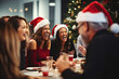three women laughing at a christmas dinner with santa hats on their heads and the woman is wearing a red hat