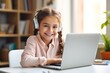 Smiling young girl wearing headphones with laptop during an online homeschooling lesson.