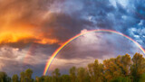 Fototapeta Tęcza - Panoramic background of stormy sky with rainbow and dramatic clouds at sunset