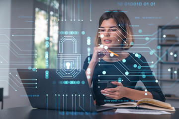 Wall Mural - Pensive attractive beautiful businesswoman in formal wear working on laptop talking on pphone in the office. Concept of data protection information technology. lock icon hologram.