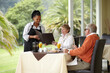 © Thomas Talkner/peopleimages.com - Waitress, menu and senior couple in restaurant on romantic date together on hotel terrace. Old man, woman and server with breakfast, food card and relax in luxury hospitality, fine dining and choice.