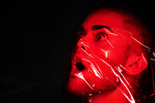 Man, Red Plastic And Suffocate In Studio Isolated On A Black Background Mockup. Polyethylene, Film And Person With Depression, Fear And Anxiety, Stress And Mental Health Crisis, Psychology And Neon