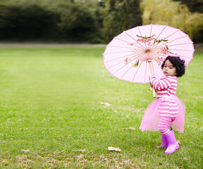 Canvas Print - Umbrella, walking and girl child in a garden walking on the grass on summer weekend. Adorable, playful and young kid, baby or toddler with curly hair playing on the lawn in outdoor field or park.