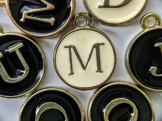 white and gold initial 'M' pendant in the middle of several letters