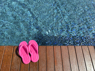 Canvas Print - Clear rippled water in swimming pool and pink flip-flops on wooden deck outdoors, above view. Space for text