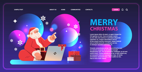 Wall Mural - santa claus in red costume sitting lotus pose, using laptop and pointing finger at something happy new year merry christmas holidays celebration