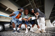 © Seventyfour - African American boy band consisting of three hip hop performers bending over ground and looking at camera against car with open door