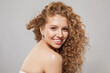 © artmim - Beautiful joyful model woman with wavy hairstyle having fun on gray background. Pretty young woman with curly hair, clear skin, natural makeup and cute smile
