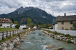 Ein kleiner Fluss durch Toblach in Südtirol mit Bergpanorama im Hintergrund