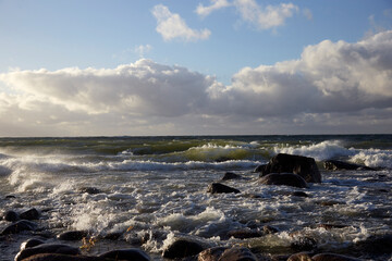 Windy day on the seashore with waves on the sea and cloudy sky above, selective focus