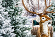 Winter holiday street decoration. Christmas store decoration. The figure of an artificial deer with a sleigh against the backdrop of a snowy forest.