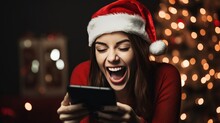 Joyful Christmas News: A Girl In A Santa Hat, Overjoyed By Good News On Her Smartphone, Celebrates The Holiday With Excitement And Cheer