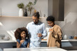 © fizkes - Happy millennial Black parents and little daughter kid keeping healthy nutrition, drinking clean natural water in kitchen, using transparent glasses, talking, smiling, laughing. Family healthcare