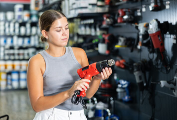 Canvas Print - Beautiful young woman chooses and buys industrial hair dryer in local hardware store