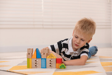 Canvas Print - Cute little boy playing with wooden toys indoors, space for text