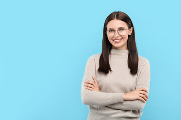 Wall Mural - Portrait of smiling woman in stylish eyeglasses on light blue background. Space for text