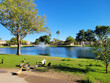 Ducks on a green grass next to blue water lake in Dos Lagos park recreation area, Glendale, Arizona