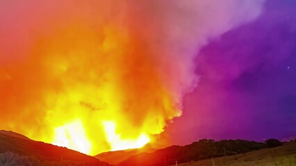 Wall Mural - Timelapse shot of an intense wildfire behind the mountains at night