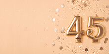 45 Years Celebration. Greeting Banner. Gold Candles In The Form Of Number Forty Five On Peach Background With Confetti.