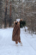 © Irina - a girl with a bouquet of fir branches walks through the winter forest